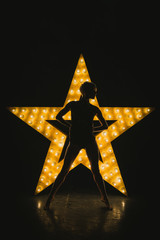 The girl is dancing against the backdrop of a glowing star