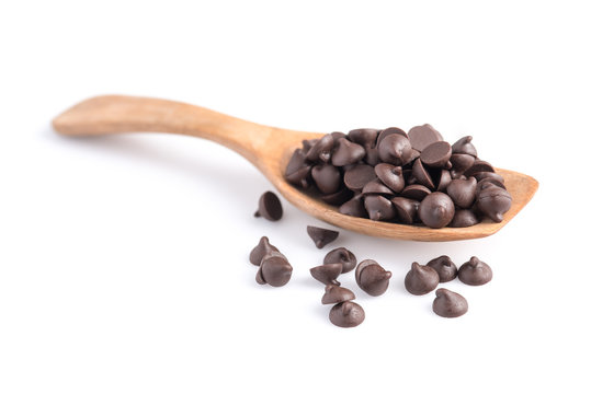 Dark chocolate chips in spoon isolated on white background.