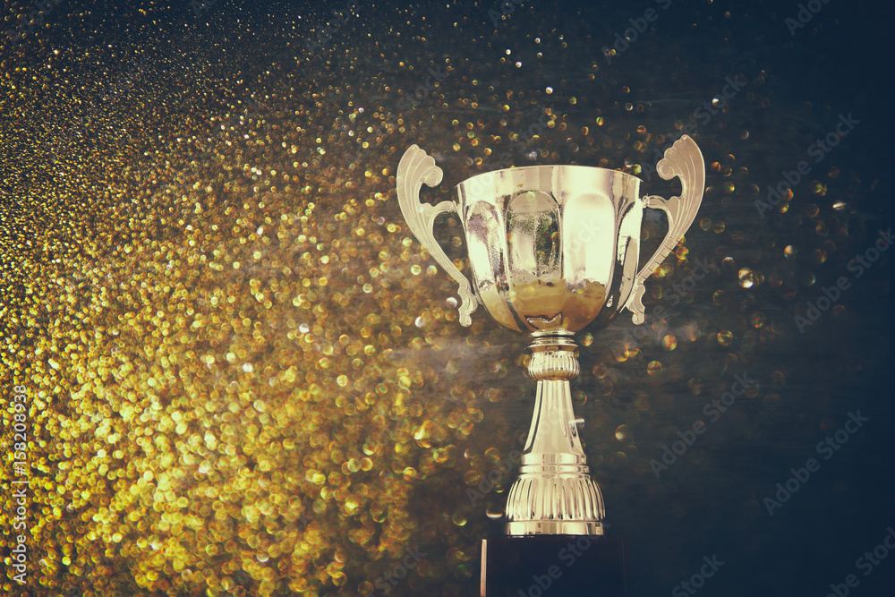 Wall mural low key image of trophy over wooden table and dark background