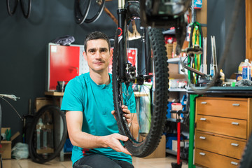 Male master is repairing the bicycle in a special workshop