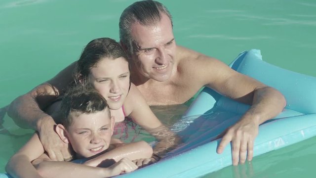Father with two children relaxing in water