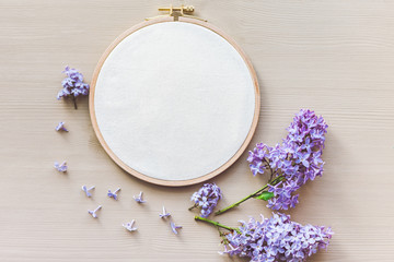 Flat lay top view photo of a mockup with embroidery hoop and flilac flowers.