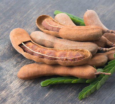 Sweet ripe tamarind pods with tamarind leaves on wood background