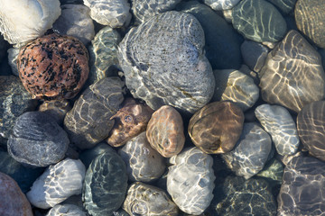 Ripples of the crystal clear shallow water surface, on a stony beach of Lake Huron, Ontario, Canada.