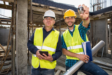 Man in hardhat and green jacket posing on building site