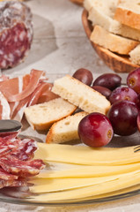 Close up ofGruyere cheese, grapes, salami, glass, red wine, cork, cheese knife, wood serving board, parings, tasty, savory healthy, lifestyle, wood bowl, brushchetta, artisan knife, italinan bread