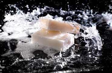 Soap bar with splashes of water on the dark background