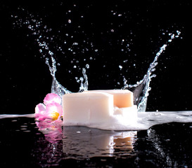 Soap bar with splashes of water on the dark background