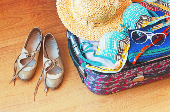 Preparation for a travel. Outfit of young woman. Different objects in a suitcase.

