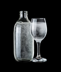 Bottle and glass of sparkling water over dark background