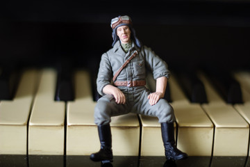 toy military man sits on the keys of a piano