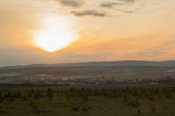 beautiful landscape with the Ural mountains, houses and railway at sunset.