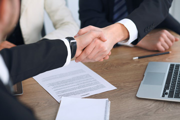 Close up of business people shaking hands at meeting or negotiation in the office. Partners are satisfied because signing contract