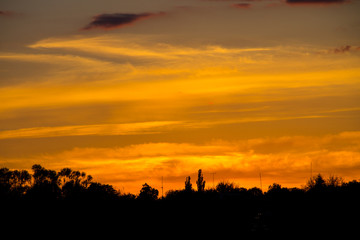 Orange sunset over silhouettes of village and trees