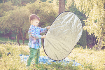 Toddler boy assists the photographer with reflector