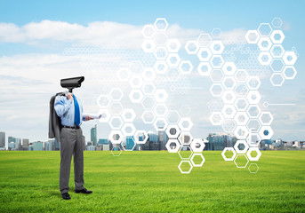 Camera headed man standing on green grass against modern cityscape