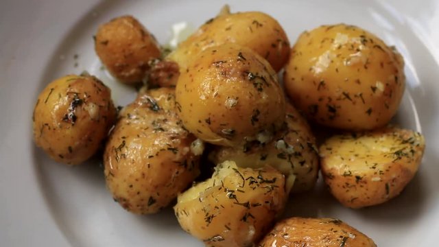 Stewed small potatoes with dill and garlic and sprinkled with parsley on a plate with wooden spoon