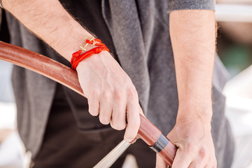 man hand with a bracelet holding a sailing vessel wheel