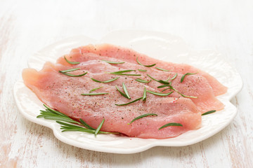 raw turkey with rosemary on white dish