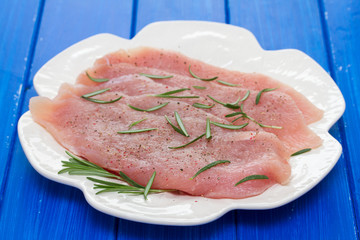 raw turkey with rosemary on white dish