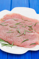 raw turkey with rosemary on white dish