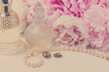 Fototapeta na wymiar Wedding lifestyle with fresh peony flowers, glamour bottles and jewellery close up, retro toned