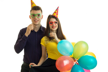 happy guy and girl with glasses and colorful balloons look forward and smiling