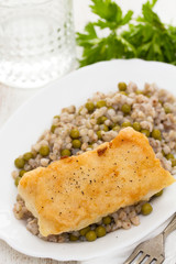 fried fish with boiled buckwheat and peas in white dish