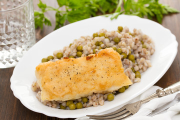 fried fish with boiled buckwheat and peas in white dish