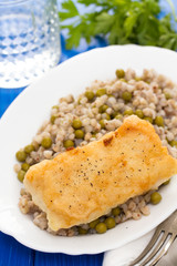 fried fish with boiled buckwheat and peas in white dish