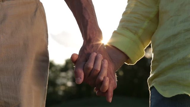 Romantic senior couple holding hands at sunset
