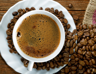 Cup with coffee on the table next to coffee beans