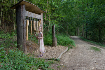 Child making music on a instrument at a sensory path in the forest