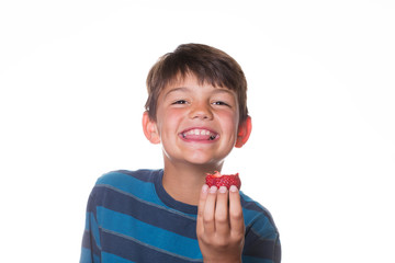 Boy smiling and holding up a strawberry