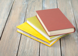 Stack of colorful books on wooden desk, free copy space. Back to school. Education background. Top view.