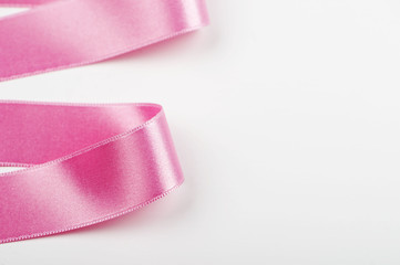 Pink ribbon with abstract shapes on white background. Copy space.