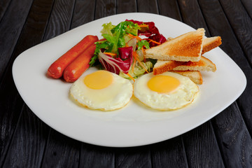 fried eggs with sausages, salad and toast
