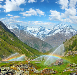 Rainbows in irrigation water spouts in Summer Alps mountain - obrazy, fototapety, plakaty