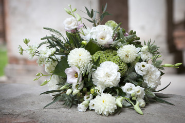 the wedding bouquet in white tones of lisianthus, roses, dahlias and eucalyptus lying on stone ancient pavement