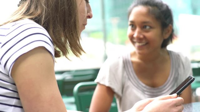 Women looking at smartphone together in outdoor cafe