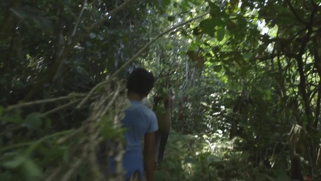 indigenous people walking in the middle of the jungle carrying wood 