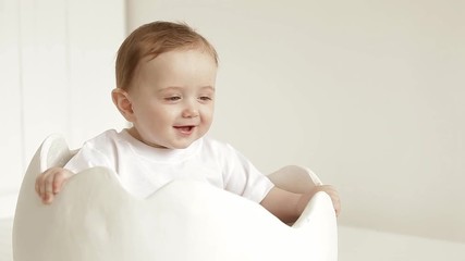 A small child is sitting in a toy egg shell.
