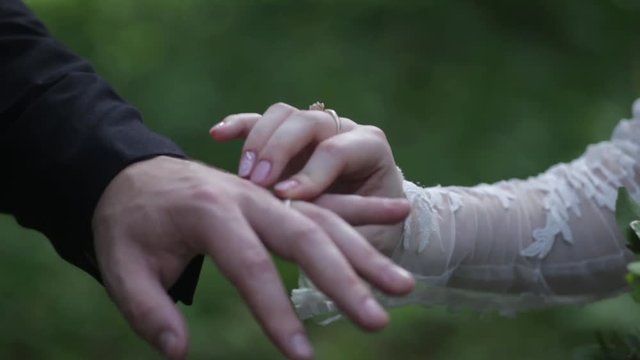 Bride wear ring on groom's finger. The groom puts the wedding ring to finger of the bride. marriage hands with rings. birde wears the ring on the finger of the groom