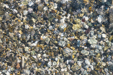 sea pebble beach with multicoloured stones, waves with foam