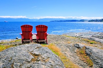 Red wooden chairs overlooking the Pacific Ocean near Victoria, BC, Canada