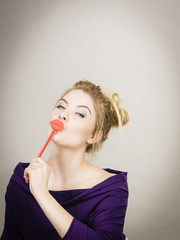 Funny woman holding big red lips on stick