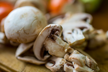Raw vegetables and mushrooms on a wooden board cut for cooking.