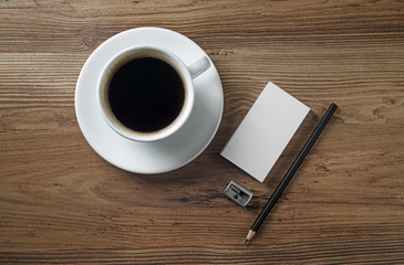 Still life with coffee. Coffee cup, saucer, bank business cards, pencil and eraser on wooden table background. Top view.