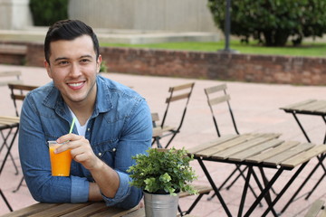 Happy man enjoying a juice outdoors 