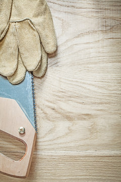 Leather safety gloves sharp handsaw on wooden board construction